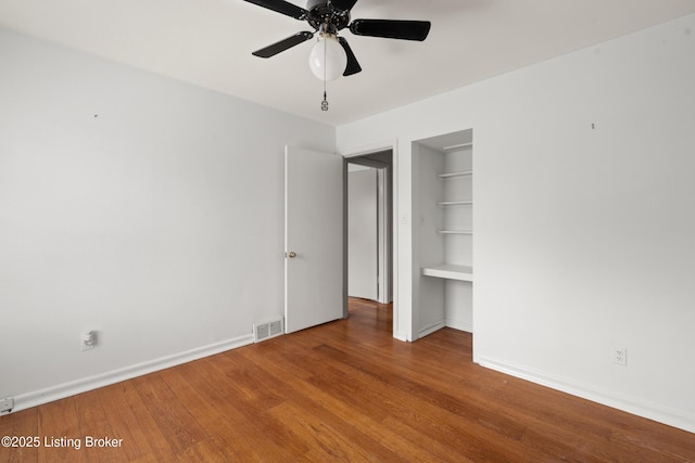 unfurnished bedroom featuring visible vents, baseboards, a ceiling fan, and wood finished floors