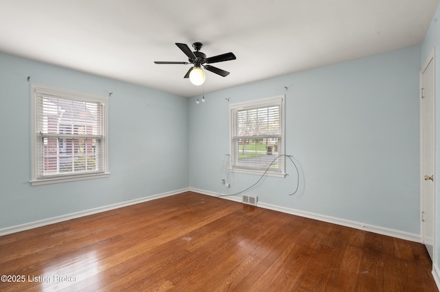 empty room with visible vents, baseboards, a ceiling fan, and wood finished floors