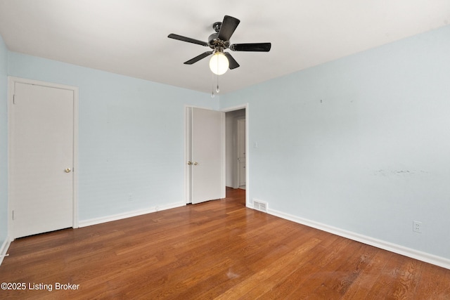 spare room featuring baseboards, ceiling fan, and wood finished floors