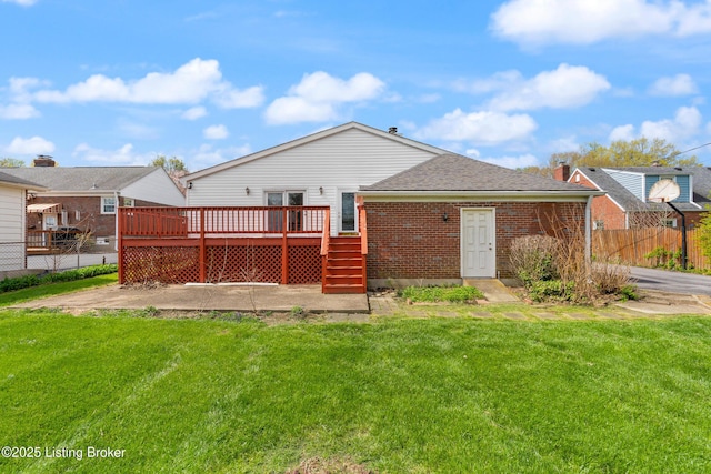 back of house with a yard, a wooden deck, fence, and brick siding