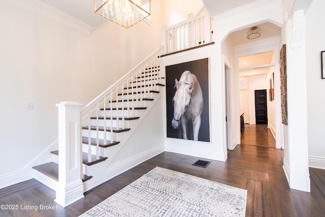 stairs with baseboards, ornamental molding, a chandelier, visible vents, and wood finished floors