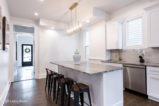 kitchen featuring dark wood-style flooring, a breakfast bar, light stone counters, white cabinets, and dishwasher