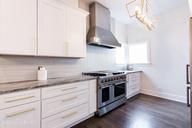 kitchen with white cabinets, wall chimney exhaust hood, double oven range, light stone countertops, and dark wood-type flooring