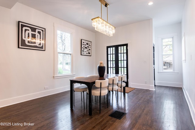 dining room with dark wood-type flooring, an inviting chandelier, baseboards, and visible vents