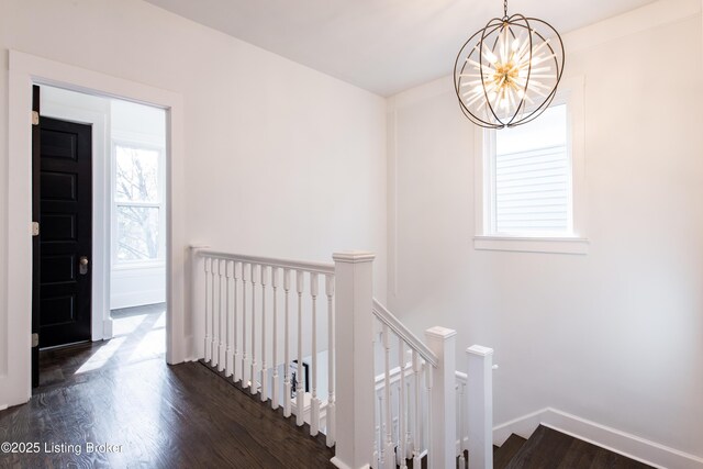 stairway featuring baseboards, a notable chandelier, and wood finished floors