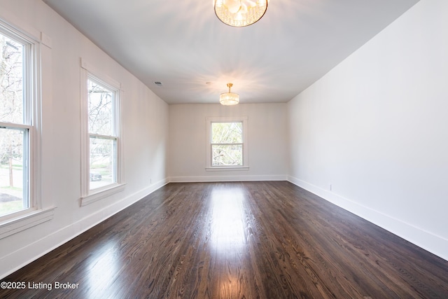 spare room featuring visible vents, baseboards, a notable chandelier, and dark wood-style floors