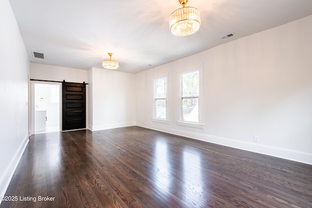 spare room with a notable chandelier, visible vents, and a barn door