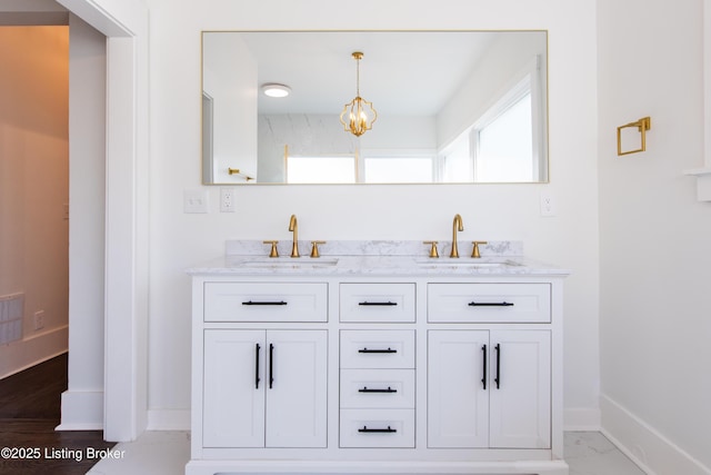 bathroom featuring marble finish floor, double vanity, a sink, and baseboards