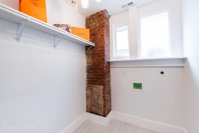 laundry room with laundry area, electric dryer hookup, visible vents, washer hookup, and baseboards