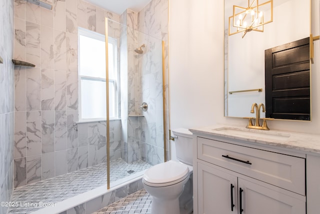 bathroom featuring a tile shower, toilet, an inviting chandelier, and vanity