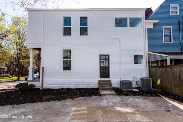 back of house with entry steps, central AC unit, and fence