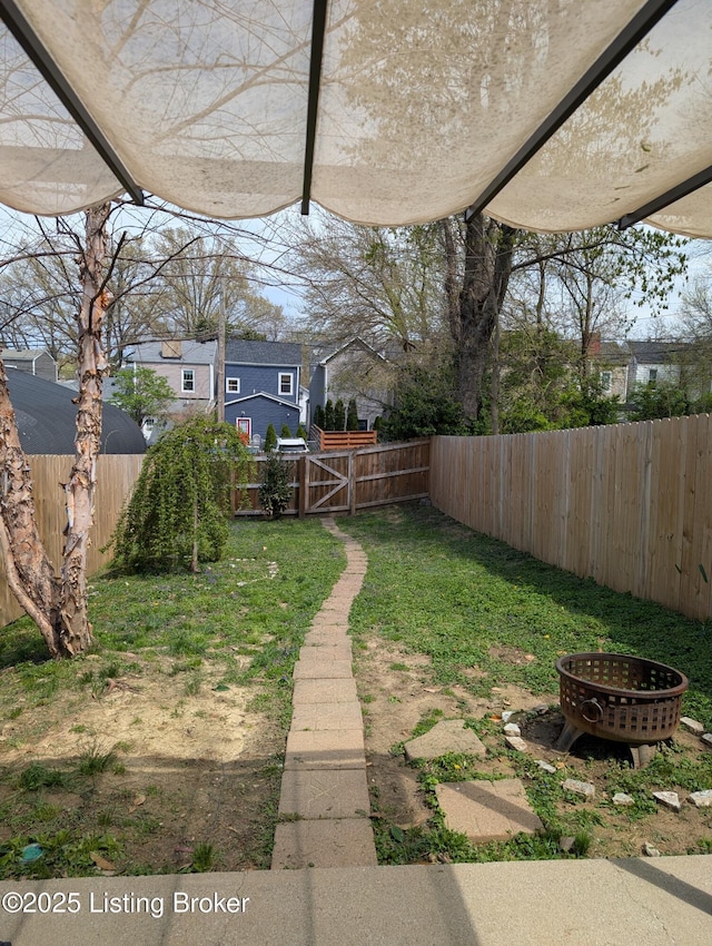 view of yard featuring a fenced backyard, a fire pit, and a gate