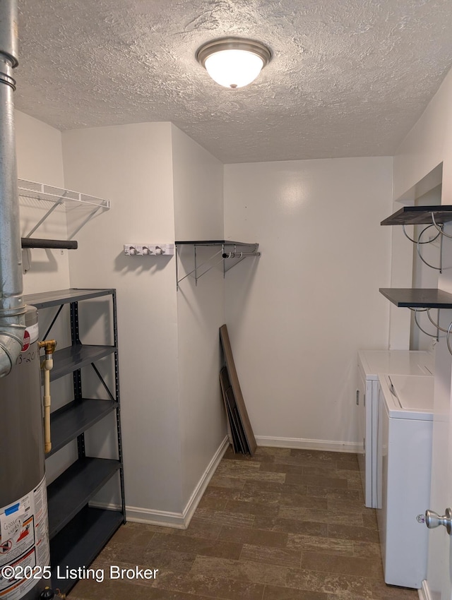 laundry area with baseboards, gas water heater, laundry area, washer and dryer, and wood finished floors
