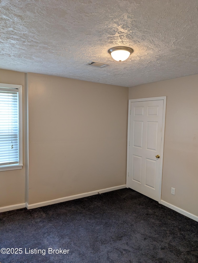 empty room featuring visible vents, baseboards, dark carpet, and a textured ceiling