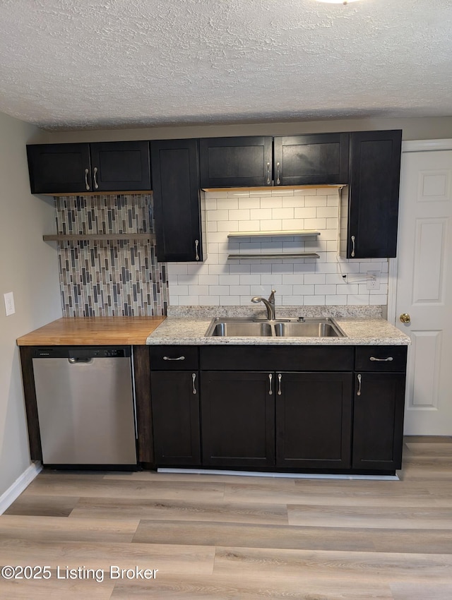 kitchen with stainless steel dishwasher, light wood-type flooring, a sink, and backsplash