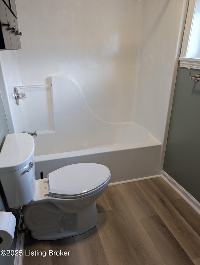 full bath featuring  shower combination, baseboards, toilet, and wood finished floors