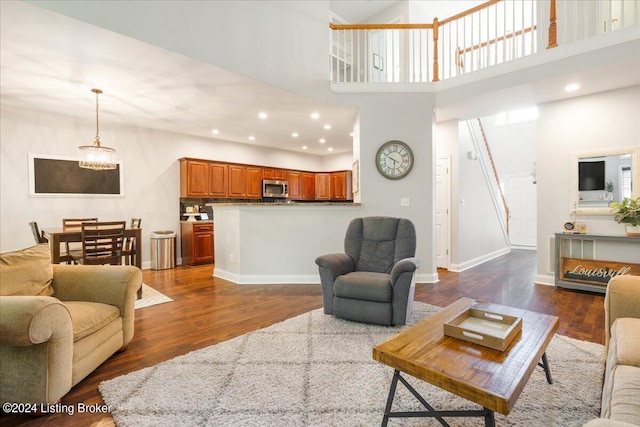 living room featuring baseboards, an inviting chandelier, dark wood finished floors, recessed lighting, and a towering ceiling