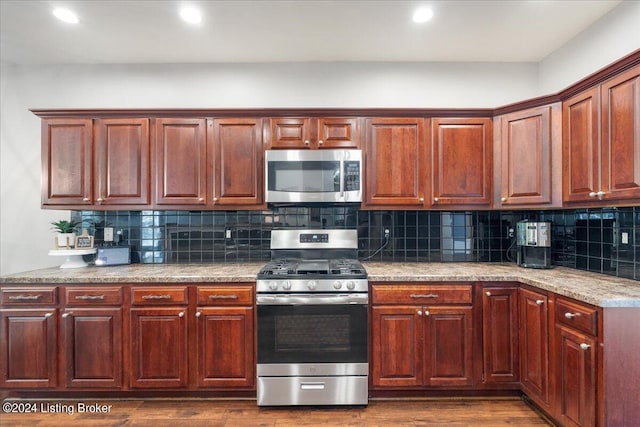 kitchen featuring stainless steel appliances, tasteful backsplash, and dark wood finished floors