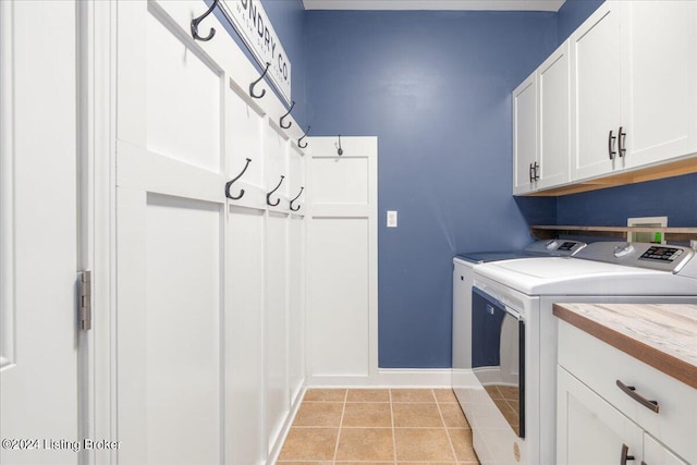 laundry area featuring separate washer and dryer, light tile patterned floors, baseboards, and cabinet space