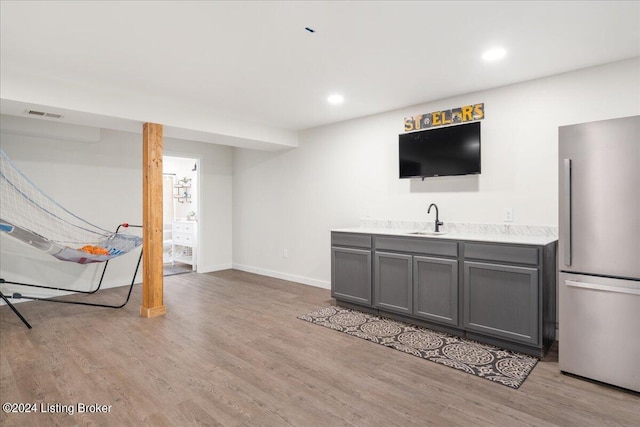 interior space with a sink, visible vents, light wood-style flooring, and freestanding refrigerator