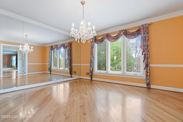 unfurnished dining area with a notable chandelier, baseboards, crown molding, and wood finished floors
