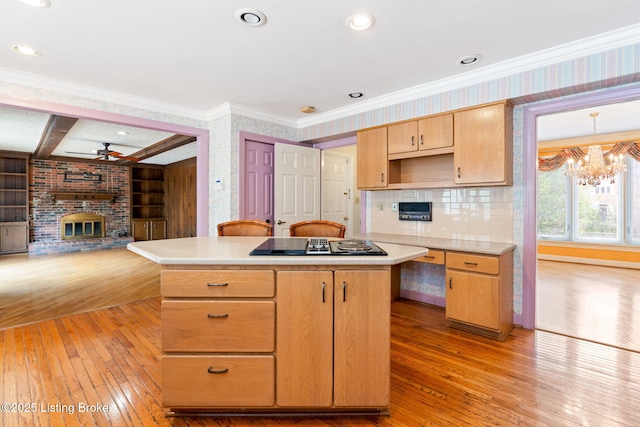 kitchen with light countertops, a brick fireplace, a kitchen island, and light wood-style floors