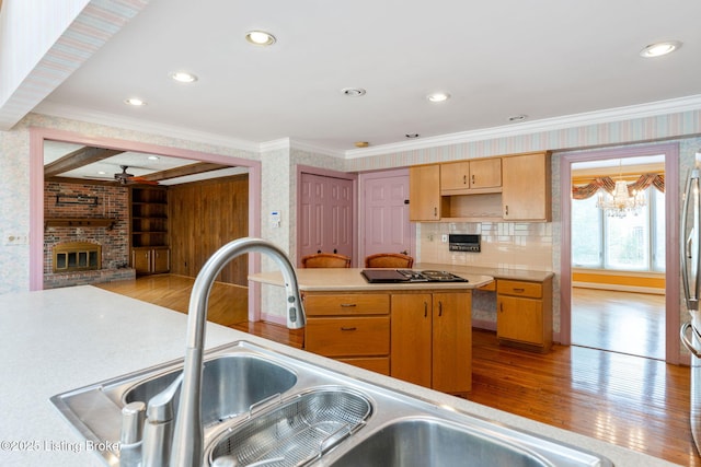 kitchen with black stovetop, light wood-type flooring, a brick fireplace, and crown molding