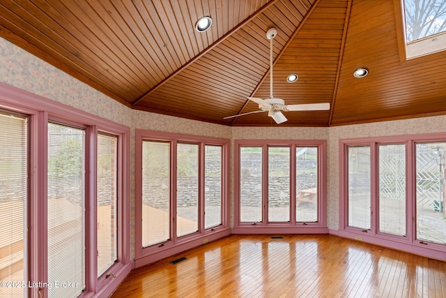 unfurnished sunroom featuring plenty of natural light, vaulted ceiling with skylight, and wallpapered walls