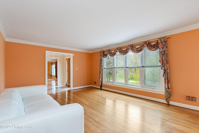 unfurnished living room featuring ornamental molding, baseboards, wood finished floors, and visible vents