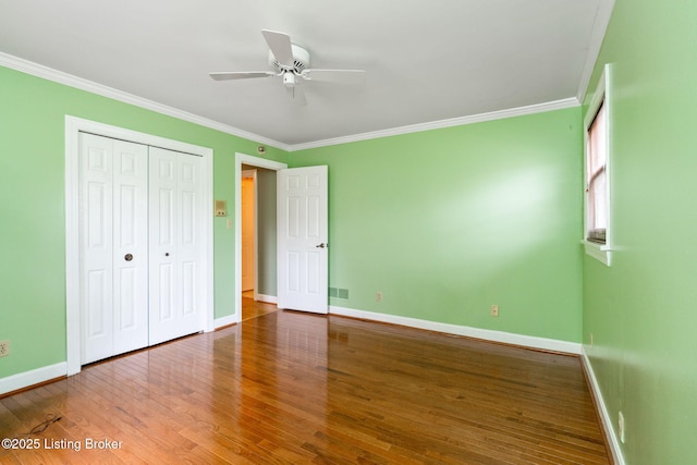 unfurnished bedroom with crown molding, wood finished floors, baseboards, and visible vents