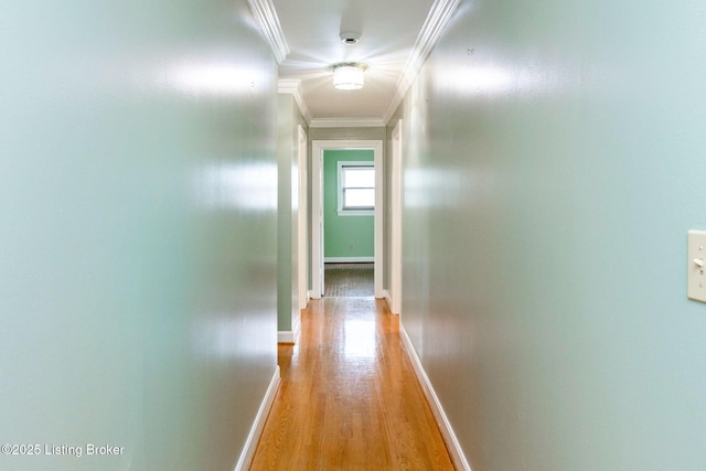 hall with light wood-type flooring, baseboards, and ornamental molding