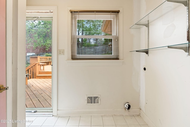 laundry room featuring laundry area, electric dryer hookup, tile patterned flooring, visible vents, and baseboards