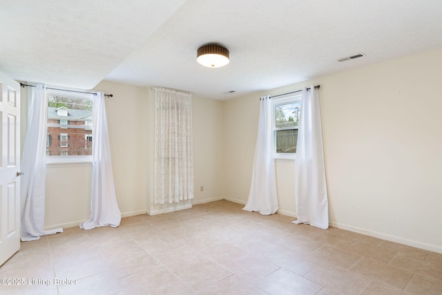 unfurnished room with light tile patterned flooring, baseboards, and visible vents