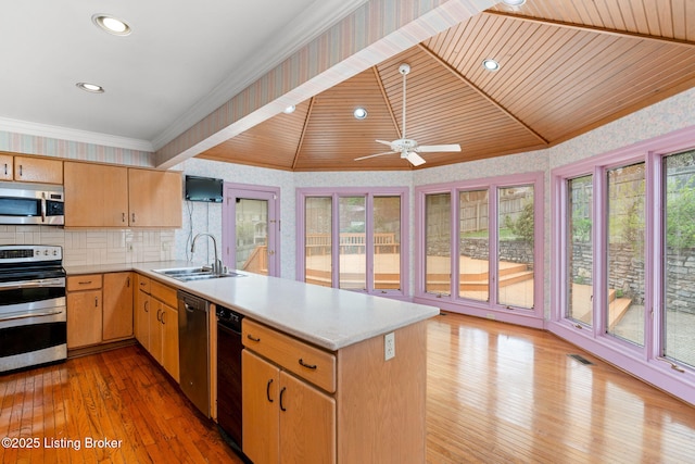 kitchen featuring stainless steel appliances, a peninsula, light countertops, and a sink