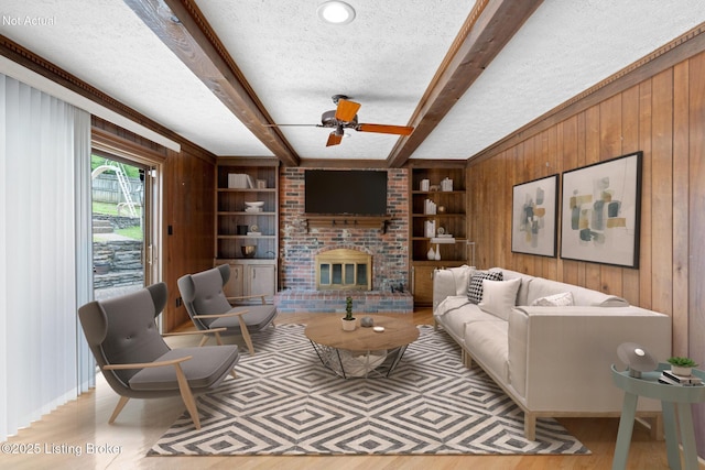 living room with built in features, a fireplace, a textured ceiling, beam ceiling, and wood walls