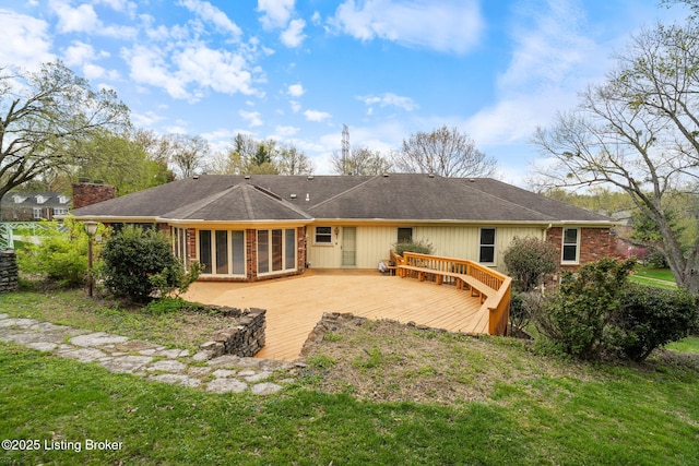 rear view of property with a chimney, a yard, a wooden deck, and brick siding
