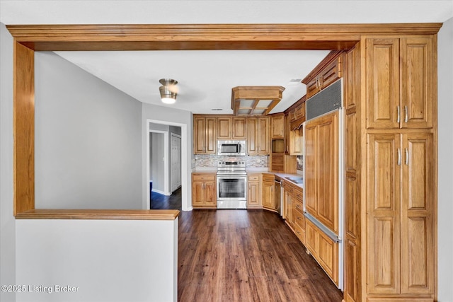 kitchen with backsplash, dark wood finished floors, light countertops, and stainless steel appliances