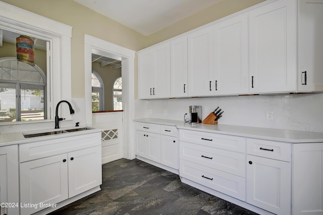 kitchen with light countertops, stone finish floor, a sink, and white cabinetry