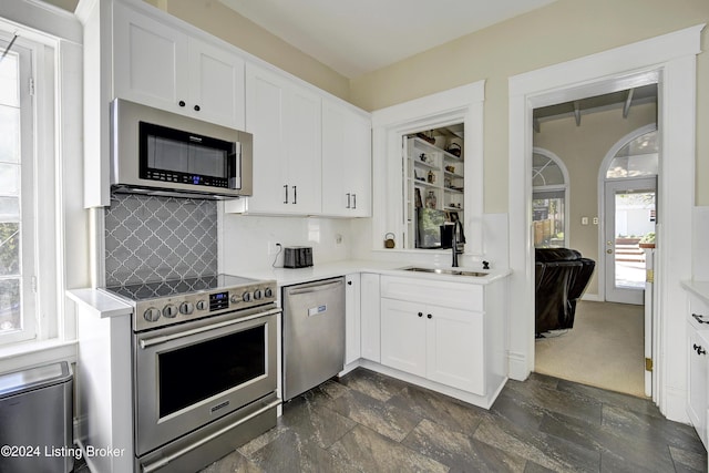 kitchen featuring tasteful backsplash, light countertops, white cabinetry, appliances with stainless steel finishes, and a sink