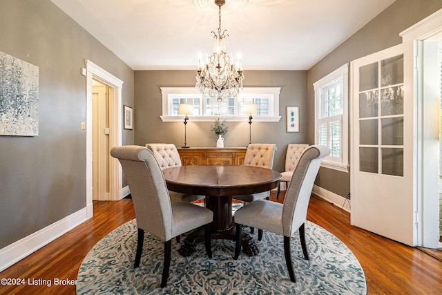 dining space with a notable chandelier, baseboards, and wood finished floors