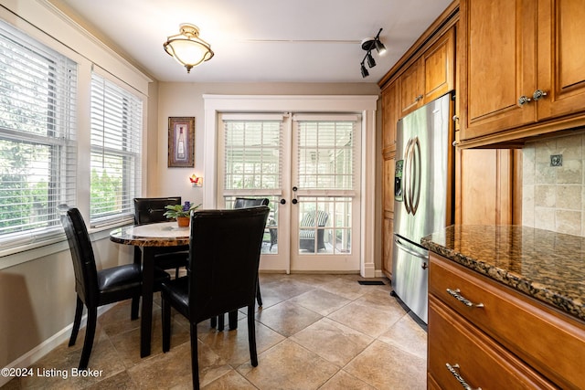 dining space featuring french doors, light tile patterned flooring, baseboards, and rail lighting