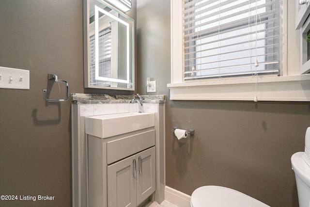 bathroom featuring toilet, vanity, and baseboards