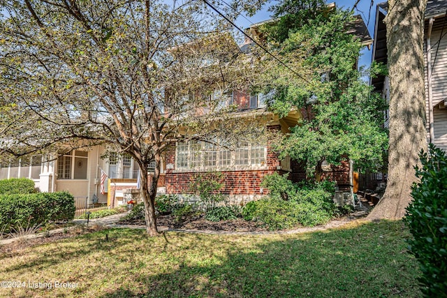 rear view of house featuring a yard and brick siding