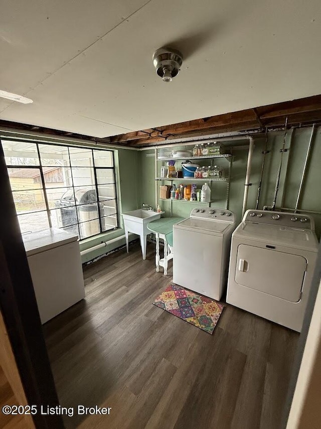 clothes washing area with laundry area, wood finished floors, a sink, and washer and clothes dryer