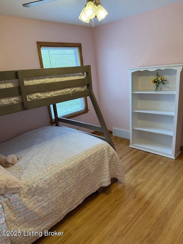 bedroom featuring wood finished floors, baseboards, and visible vents