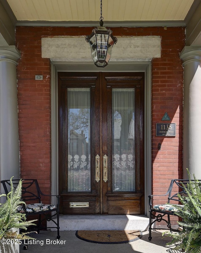 doorway to property featuring brick siding and covered porch