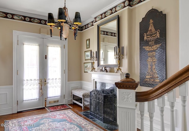 entryway featuring french doors, a wainscoted wall, a chandelier, and wood finished floors