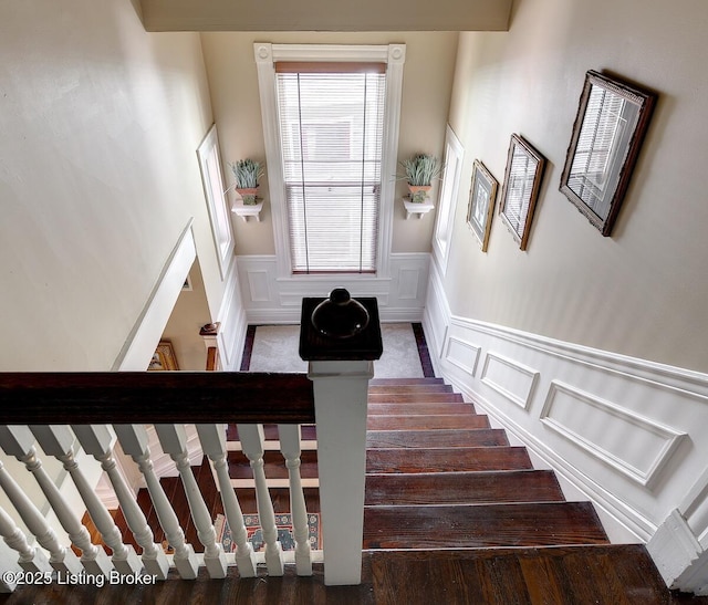 stairway featuring a decorative wall and a wainscoted wall