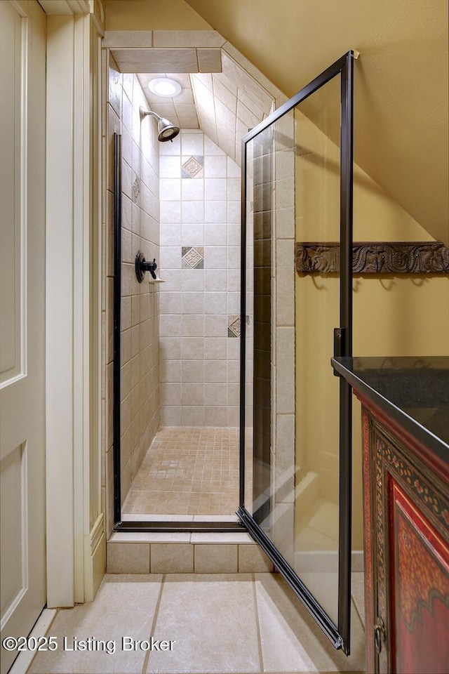 bathroom with a shower stall, tile patterned floors, and lofted ceiling