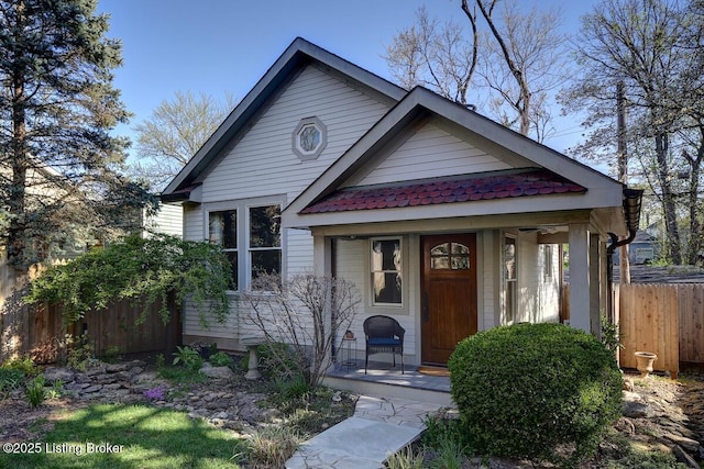 bungalow-style home featuring a porch and fence